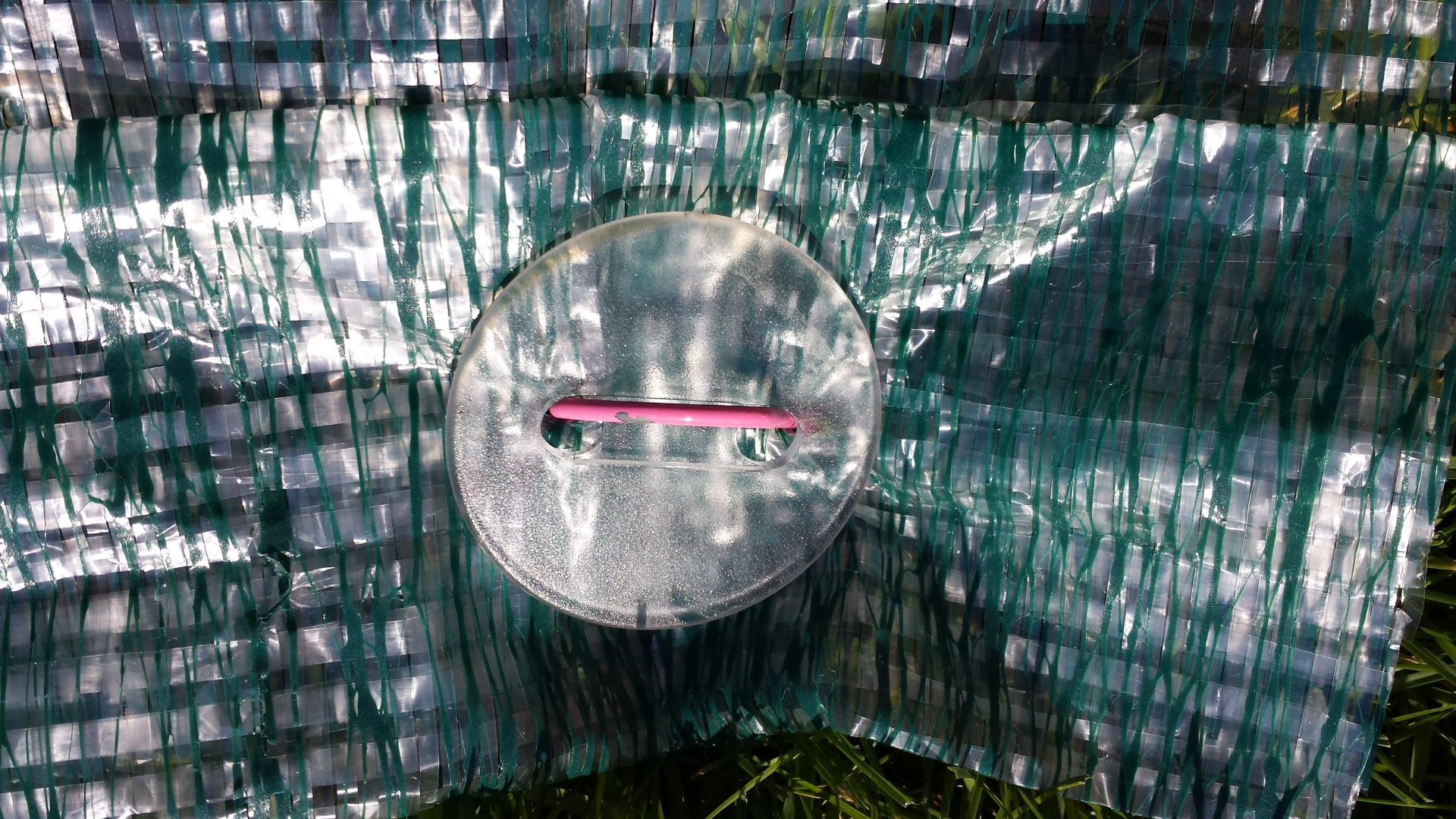 Evergreen Cover Disk fastening a turf cover to the ground with a pink sod staple